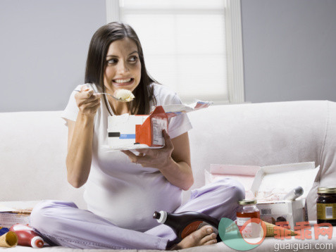 饮食,休闲活动,健康保健,人类生殖,人生大事_56959714_Pregnant woman sitting on a couch and eating ice-cream_创意图片_Getty Images China