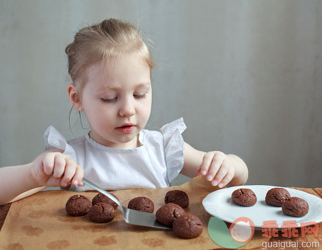 厨房,人,饮食,食品,刮刀_555756239_Little girl puts the chocolate cookies on a plate_创意图片_Getty Images China