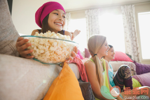 人,饮食,食品,生活方式,室内_485208915_Smiling girl holding popcorn bowl at slumber party_创意图片_Getty Images China