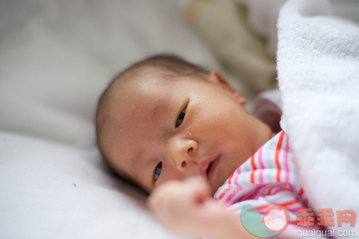 人,婴儿服装,床,室内,褐色眼睛_479779979_A baby is looking at her own hand in blanket_创意图片_Getty Images China