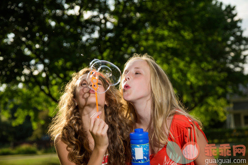 人,度假,户外,庭院,微笑_159626620_Two girls blowing bubbles with bubble wand_创意图片_Getty Images China