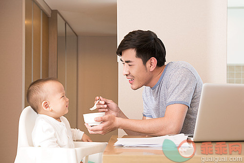 东亚人,室内,人,生活方式,家庭生活_0e3b56784_Young father working while feeding baby boy_创意图片_Getty Images China