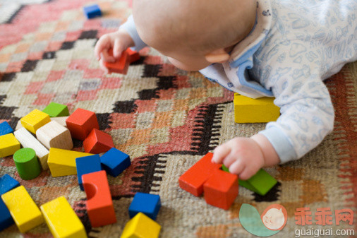 概念,主题,休闲活动,家庭生活,构图_73347578_Baby boy (6-9 months) playing with wooden blocks on patterned rug_创意图片_Getty Images China