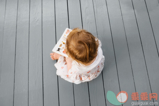 人,休闲装,玩具,12到17个月,室内_126159720_High angle view of a baby girl sitting on the floor and looking at a picture book_创意图片_Getty Images China