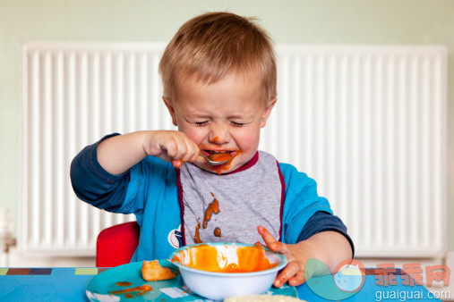 人,婴儿服装,食品,桌子,12到17个月_494826947_Young boy pulling faces whilst eating_创意图片_Getty Images China