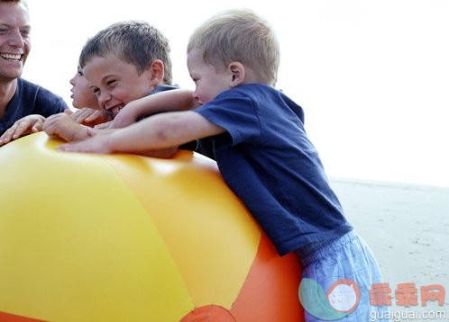 旅行,度假,摄影,户外,三个孩子的家庭_10186780_Man and children (4-6) playing with beachball on beach, close-up_创意图片_Getty Images China