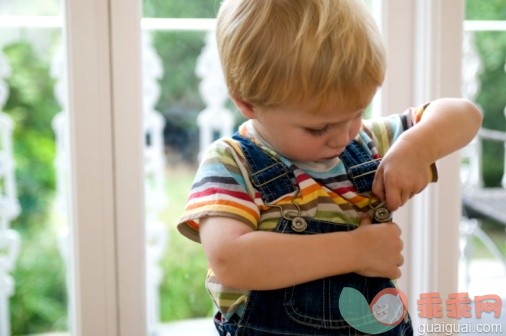 人,室内,金色头发,窗户,看_91627344_Blonde toddler fastening buttons on dungarees, close-up_创意图片_Getty Images China