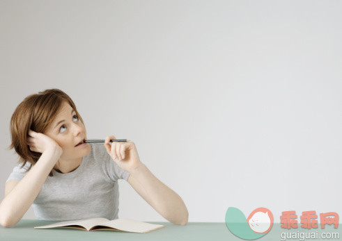 教育,摄影,Y50923,肖像,看_pha295000017_Young woman sitting with open notebook, holding pencil to mouth_创意图片_Getty Images China