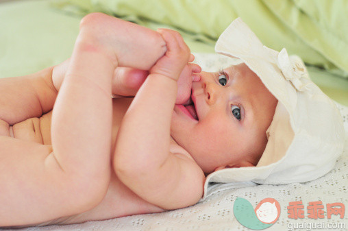 人,婴儿服装,床,室内,蓝色眼睛_147456071_Nude baby girl lying with foot in its mouth_创意图片_Getty Images China