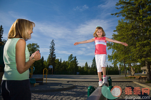 表,人,休闲装,户外,40到44岁_557061019_A Mother Watches As Her Young Daughter Walks On A Balance Beam At A School Playground In Anchorage, Alaska During Summer_创意图片_Getty Images China