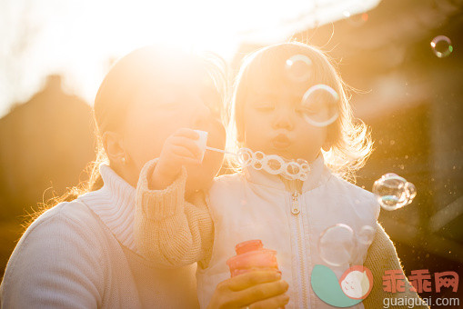 人,寒冷,户外,庭院,父母_563395557_Mother and child blowing together soap bubbles_创意图片_Getty Images China