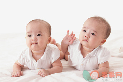 人,婴儿服装,影棚拍摄,室内,伸手_558986713_Cute twins lying on front and looking away together_创意图片_Getty Images China