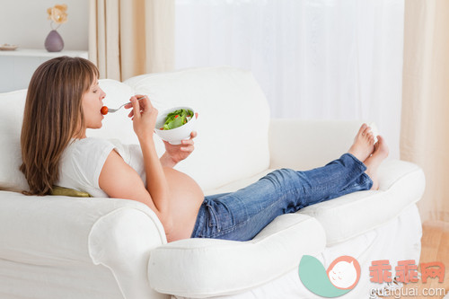 30岁到34岁,美女,美,肚子,碗_gic9717978_Pretty pregnant woman eating a salad while lying on a sofa in her apartment_创意图片_Getty Images China