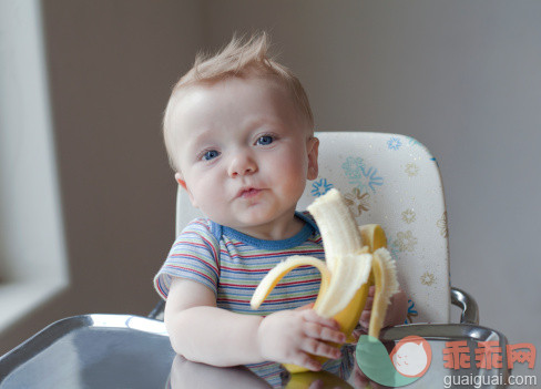 人,饮食,休闲装,椅子,T恤_145652757_Baby boy holding a banana in high chair._创意图片_Getty Images China