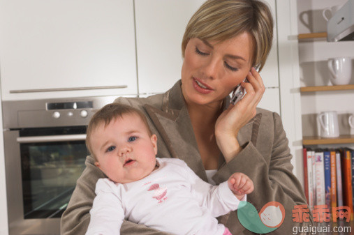 矮,忙碌,相机,厨房,人_78234583_portrait of young businesswoman in kitchen holding baby and talking on mobile phone_创意图片_Getty Images China