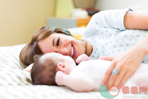 进行中,人,休闲装,床,T恤_562612201_Smiling mother lying on bad with baby boy (6-11 months)_创意图片_Getty Images China