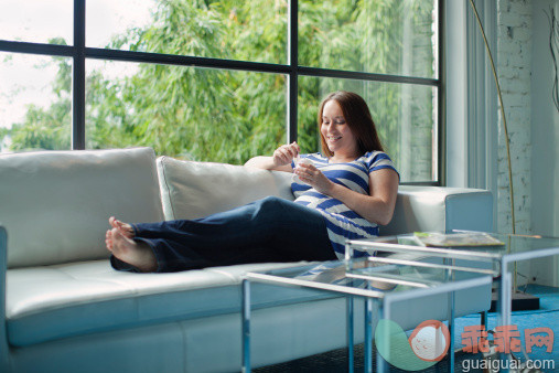 人,饮食,沙发,人生大事,室内_112704566_Pregnant Caucasian woman eating on sofa_创意图片_Getty Images China