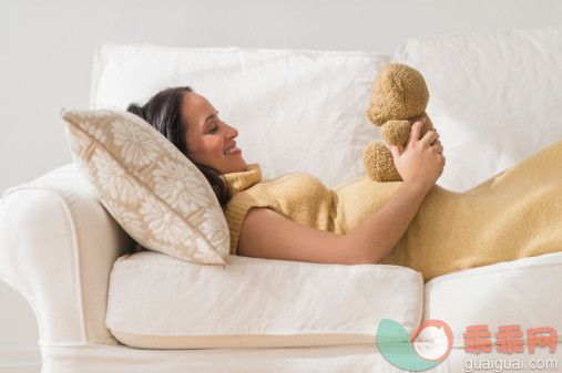 人,沙发,人生大事,生活方式,四分之三身长_494324339_Pregnant Hispanic woman admiring teddy bear_创意图片_Getty Images China