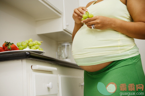 饮食,健康食物,休闲活动,家庭生活,生活方式_55974234_Pregnant woman eating fruit in kitchen_创意图片_Getty Images China