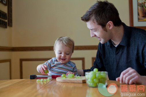 人,饮食,休闲装,桌子,室内_134074482_Father feeding toddler son fresh grapes at table._创意图片_Getty Images China