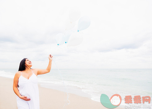 人,气球,连衣裙,人生大事,自然_554372033_Pregnant mixed race woman holding balloons on beach_创意图片_Getty Images China