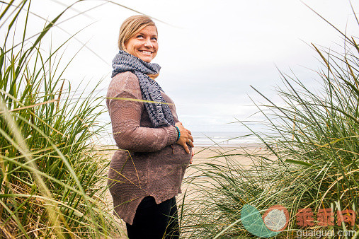 围巾,人,毛衣,环境,人生大事_526295767_Caucasian pregnant woman holding her stomach on beach_创意图片_Getty Images China