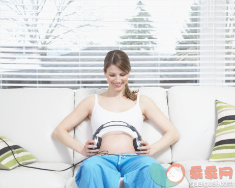 概念,主题,休闲活动,家庭生活,音乐_76038535_Pregnant woman sitting on sofa, putting headphones on stomach_创意图片_Getty Images China