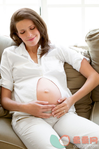 人,人生大事,四分之三身长,室内,25岁到29岁_508482729_Pregnant woman holding her belly on sofa_创意图片_Getty Images China