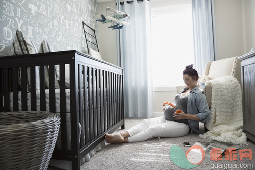 人,休闲装,人生大事,生活方式,四分之三身长_gic14287884_Pregnant woman holding headphones to stomach in nursery_创意图片_Getty Images China