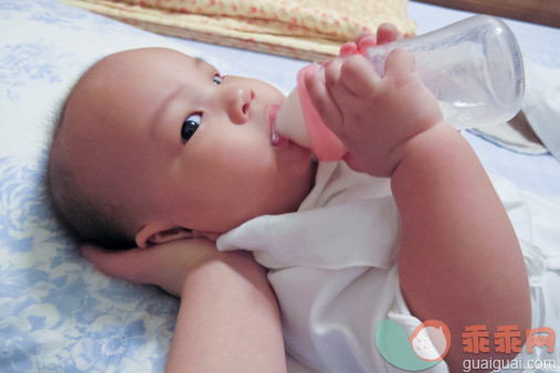 人,婴儿服装,床,室内,手_148438728_Baby holding milk bottle_创意图片_Getty Images China