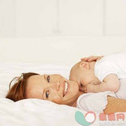 摄影,父母,母亲,室内,面部表情_stk204419rke_mother lying on a bed holding her baby (6-12 months)_创意图片_Getty Images China