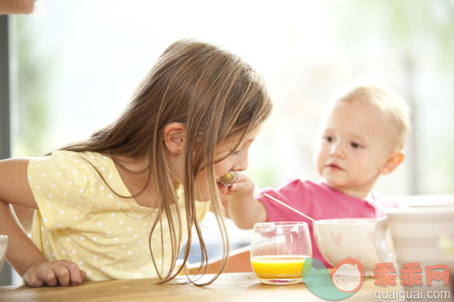 人,饮食,睡衣,饮料,桌子_gic14252486_Baby girl feeding sister at breakfast table_创意图片_Getty Images China