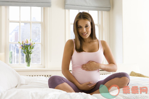 室内,人,拿着,肖像,坐_gic16389358_Young pregnant woman sitting on bed, hands on stomach, smiling, portrait_创意图片_Getty Images China