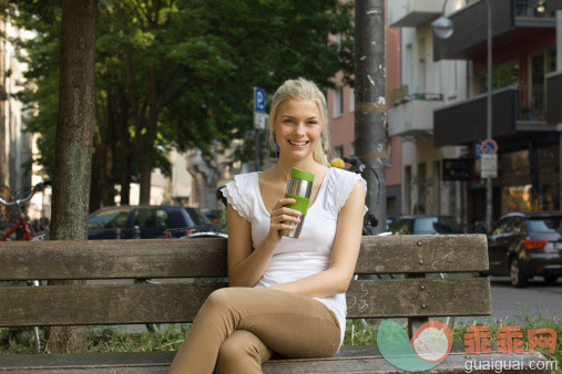 人,饮食,休闲装,饮料,循环利用_155786049_Germany, North Rhine Westphalia, Cologne, Young woman sitting on bench with coffee cup, smiling, portrait_创意图片_Getty Images China