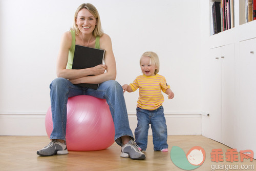 室内,人,拿着,肖像,坐_gic16389377_Woman with book on exercise ball by baby daughter (12-15 months,) smiling, portrait, low angle view_创意图片_Getty Images China