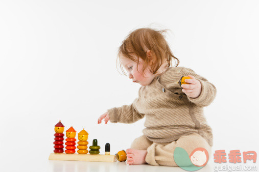 戒指,人,休闲装,玩具,影棚拍摄_153340308_A baby girl playing with a wooden stacking toy_创意图片_Getty Images China