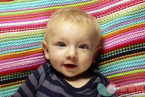 人,婴儿服装,蓝色眼睛,快乐,金色头发_506348281_Baby boy smiling in a bed with colorful background_创意图片_Getty Images China