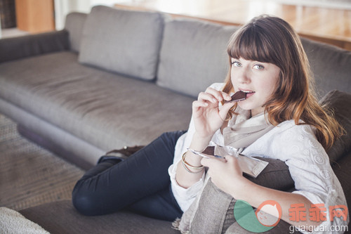 人,休闲装,沙发,生活方式,室内_gic16749337_Young woman sitting on sofa eating bar of dark chocolate_创意图片_Getty Images China