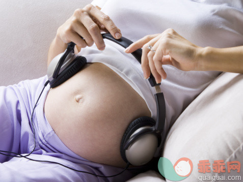 沟通,技术,休闲活动,健康保健,人类生殖_56959111_Mid section view of a pregnant woman with headphones on her abdomen_创意图片_Getty Images China