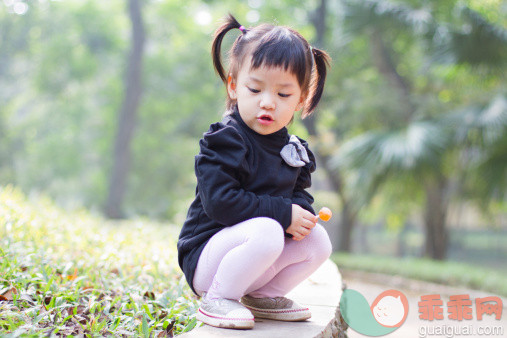 人,婴儿服装,户外,公园,蹲_112257995_Toddler girl holding lollipop in park_创意图片_Getty Images China