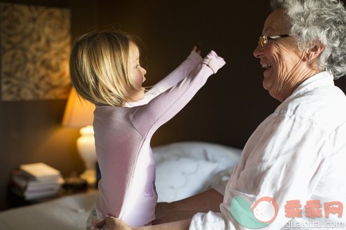 年龄对比,高举手臂,床,卧室,白人_gic14882469_Grandmother helping toddler granddaughter (2-3) get pajamas on, California, USA_创意图片_Getty Images China