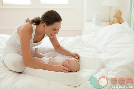 人,住宅内部,床,室内,20到24岁_107908337_Mother with baby son on changing mat_创意图片_Getty Images China