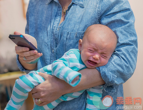 人,休闲装,沟通,2到5个月,室内_525445885_USA, New Jersey, Jersey City, Woman texting and holding crying baby boy (2-5 months)_创意图片_Getty Images China