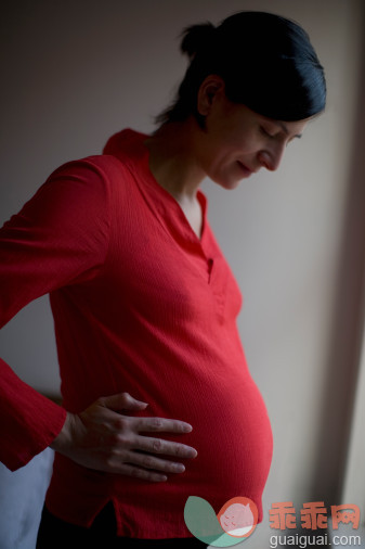 摄影,人,休闲装,室内,满意_83819766_Pregnant woman looking at stomach in window light_创意图片_Getty Images China