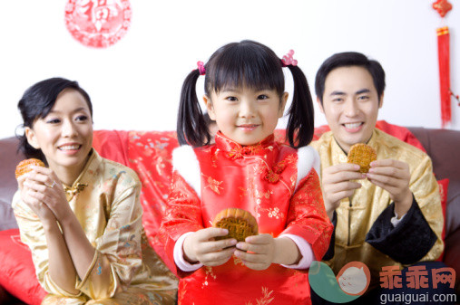 人,衣服,着装得体,食品,沙发_86460483_Young family with one child holding moon cakes and smiling happily_创意图片_Getty Images China