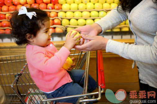 人,休闲装,婴儿服装,购物车,零售_98110647_Mother handing apple to daughter at grocery store_创意图片_Getty Images China