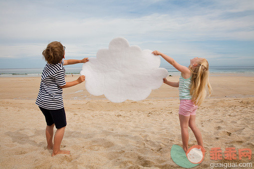休闲装,沟通,度假,互联网,太阳_556968393_Boy and girl holding a cloud on the beach_创意图片_Getty Images China