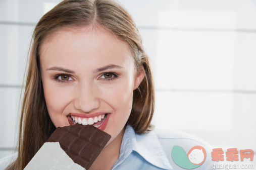 人,饮食,休闲装,甜食,室内_112230318_Germany, Cologne, Young woman eating chocolate bar, portrait_创意图片_Getty Images China