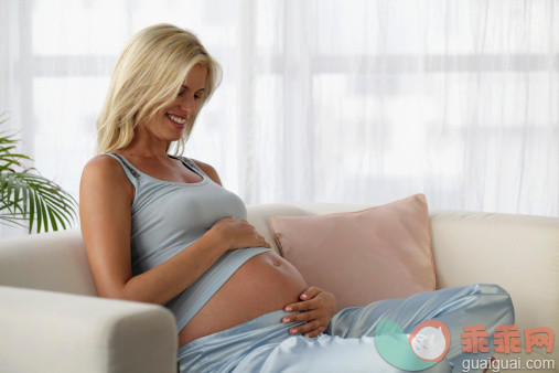 人,沙发,影棚拍摄,四分之三身长,室内_147208323_pregnant woman looking down at her belly and smiling_创意图片_Getty Images China