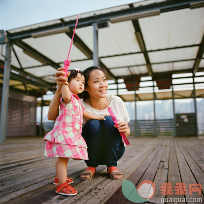 人,建筑结构,休闲装,凉鞋,户外_155112599_Mom and baby playing with bubble stick_创意图片_Getty Images China